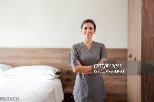 femme de chambre souriante regardant la caméra dans la chambre d’hôtel - aide ménagère photos et images de collection