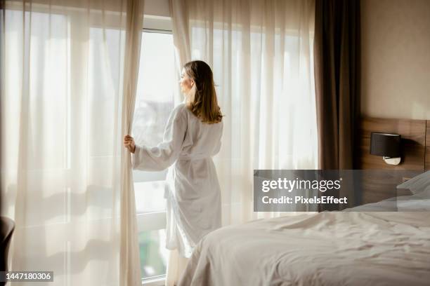 mujer disfruta de magnífica vista desde la ventana del hotel - hotel de lujo fotografías e imágenes de stock