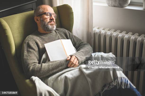 mature adult man in home interior ( book) - climate grief stock pictures, royalty-free photos & images