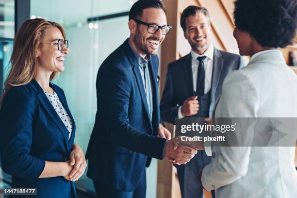 businessman and businesswoman greeting each other on a meeting - mergr stock pictures, royalty-free photos & images