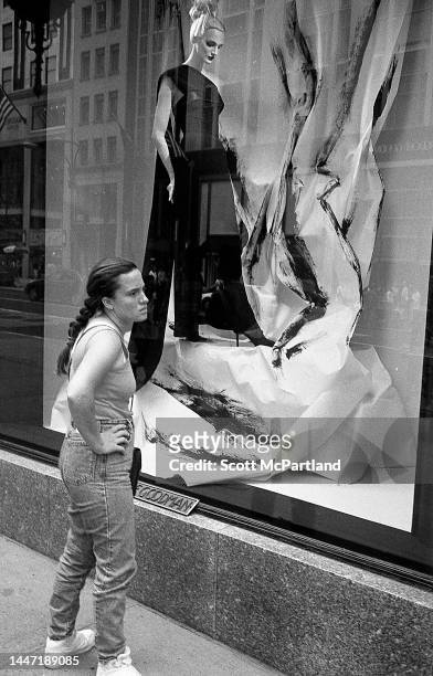View of a woman as she stands, hands on her hips, in front of a window display at the Bergdorf Goodman department store on 5th Avenue , New York, New...