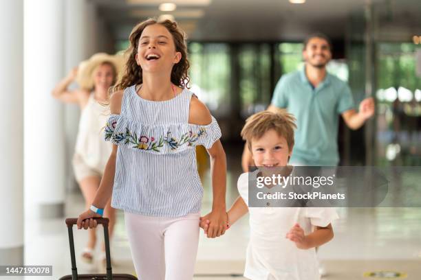 kids whit luggage running in hotel lobby - family hotel stock pictures, royalty-free photos & images