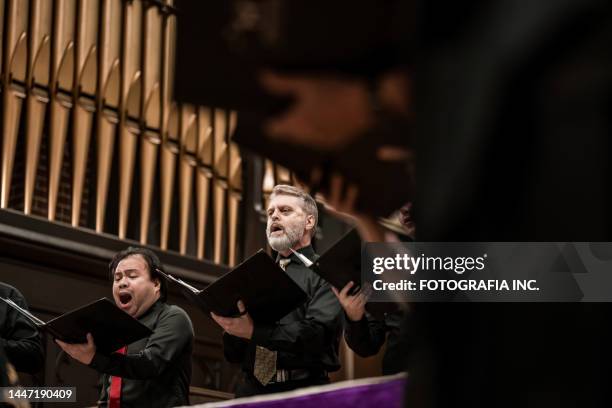 men singers in church choir during performance at concert - koor stockfoto's en -beelden