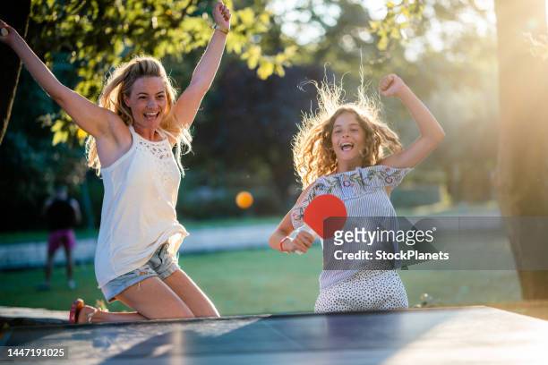 mother playing table tennis whit her daughter on summer day - women's table tennis stockfoto's en -beelden