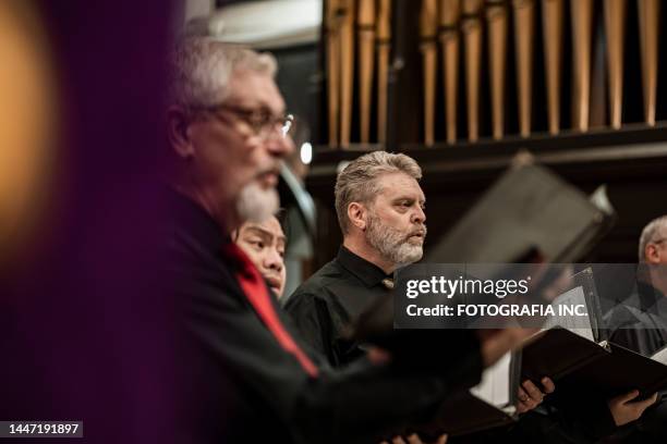 men singers in church choir during performance at concert - koor stockfoto's en -beelden