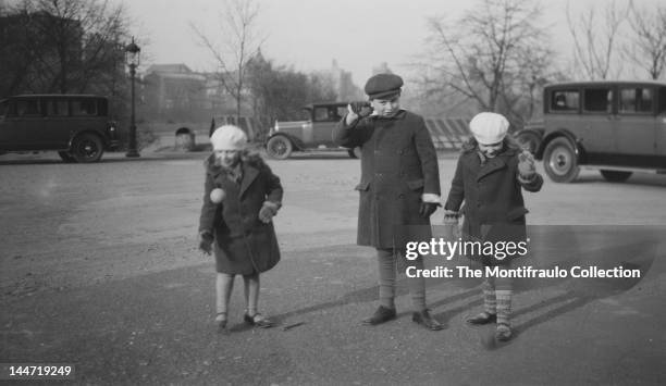 Child prodigy voilinist Yehudi Menuhin with his sisters Yaltah and Hephsibah Menuhin playing with balls in Central Park, with several parked...