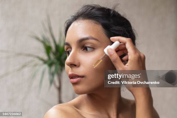 young woman applying face oil, serum - face oil stock pictures, royalty-free photos & images