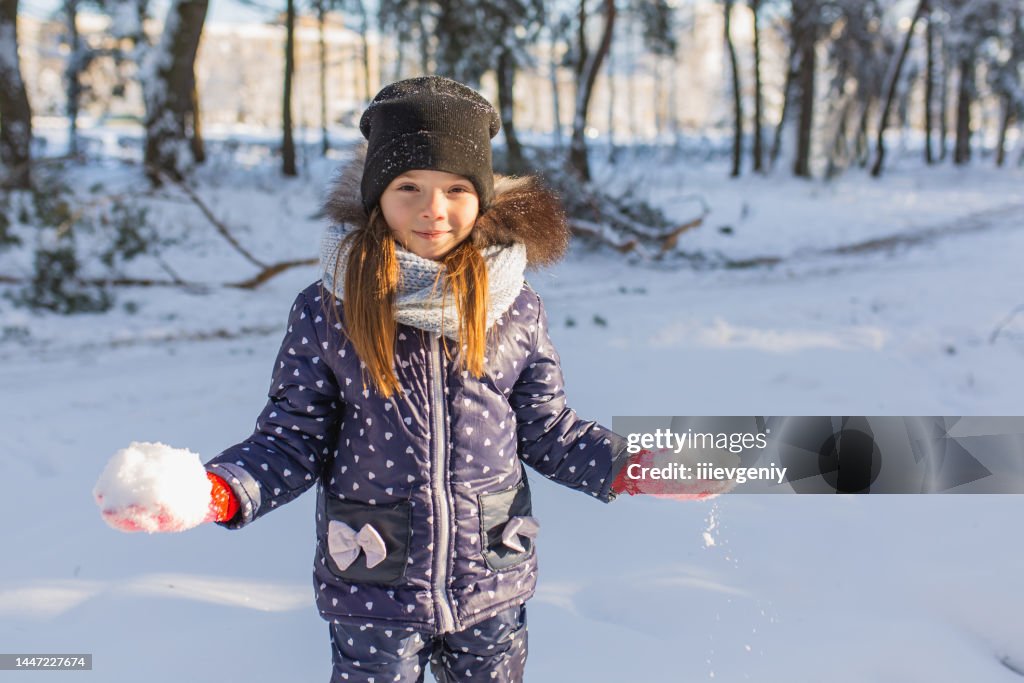 Girl play snowballs and have fun in winter forest. Running and moving. Happy childhood. Winter holiday. Deep snow. Girls. Warm clothes. Throw snow