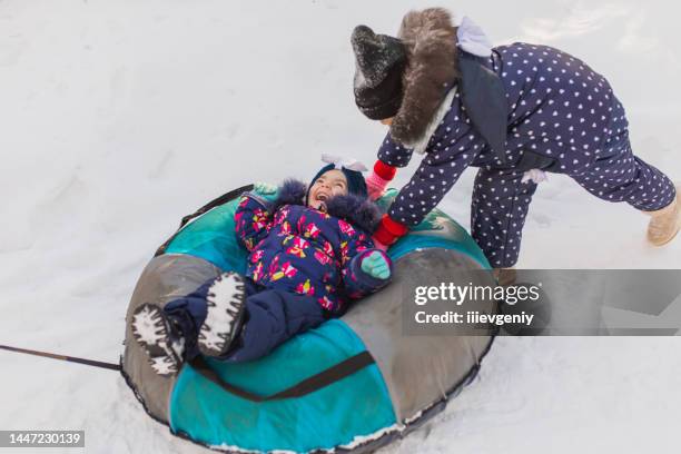 tobogganing and sledding. children play and have fun with sledge in winter forest. running and moving. happy childhood. winter holiday. deep snow. boys and girls. warm clothes. tubing - frozen action stock pictures, royalty-free photos & images