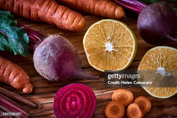 carrots, beetroot and orange fruit on old wooden board ready to cook - beetroot smoothie stock pictures, royalty-free photos & images
