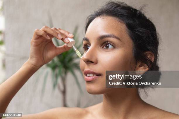 young woman applying face oil, serum - applying oil stock pictures, royalty-free photos & images