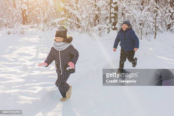 i bambini giocano e si divertono nella foresta invernale. correre e muoversi. infanzia felice. vacanze invernali. neve profonda. ragazzi e ragazze. vestiti caldi - day 6 foto e immagini stock