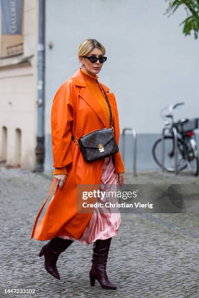 Victoria Scheu wears orange knitted jumper H&M, satin skirt H&M, bag Louis Vuitton, orange coat Nakd on December 05, 2022 in Berlin, Germany.