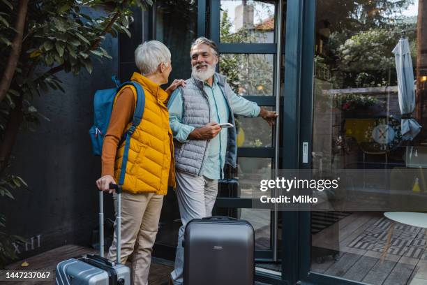 senior couple of tourists entering the rented apartment - carrying luggage stock pictures, royalty-free photos & images