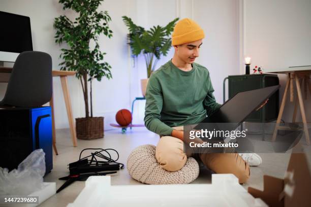 teenage boy unpacking computer monitor that he ordered for his gaming setup - receiving check stock pictures, royalty-free photos & images