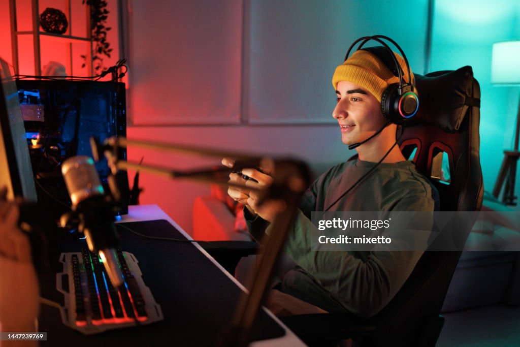 Teenage gamer playing video game in his room