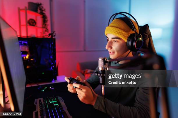 teenage boy spielen multiplayer-spiele auf desktop pc in seinem dunklen raum - luftschlange stock-fotos und bilder