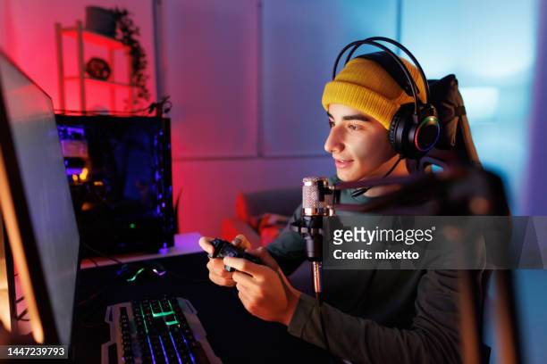teenage boy jugando juegos multijugador en pc de escritorio en su habitación oscura - streamer fotografías e imágenes de stock