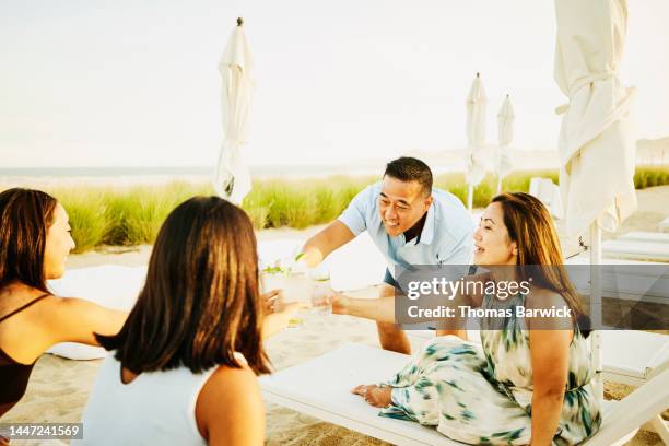 medium shot of smiling family toasting with drinks on tropical beach - beach cocktail stock pictures, royalty-free photos & images