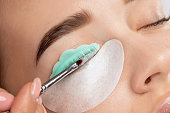Make-up artist makes the procedure of lamination and dyeing of eyelashes to a beautiful woman in a beauty salon. Eyelash extensions. Eyelash lifting