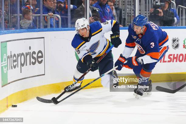 Marco Scandella of the St. Louis Blues battles for the puck with Adam Pelech of the New York Islanders in the first period at UBS Arena on December...