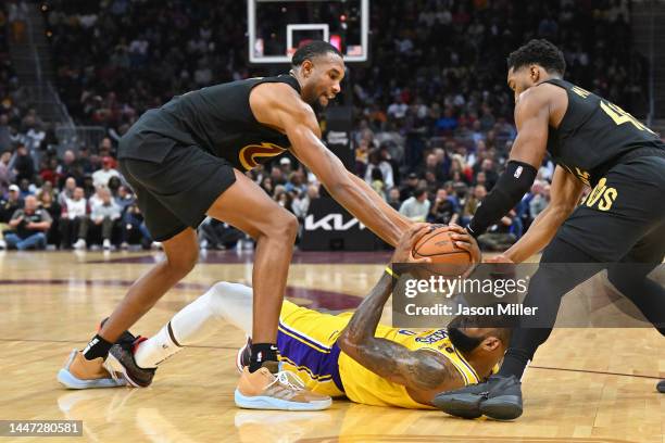 LeBron James of the Los Angeles Lakers fights for a loose ball with Evan Mobley and Donovan Mitchell of the Cleveland Cavaliers during the third...