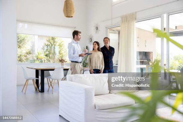 real estate agent showing a house for sale to a couple - estate agent stock pictures, royalty-free photos & images