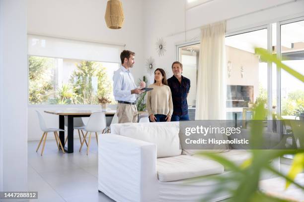 real estate agent showing a house for sale to a couple - real estate agent stock pictures, royalty-free photos & images