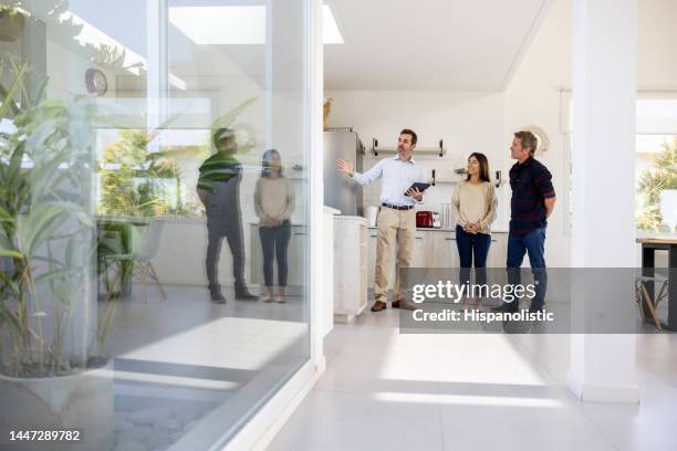 real estate agent showing a house for sale to a couple - bens imóveis imagens e fotografias de stock