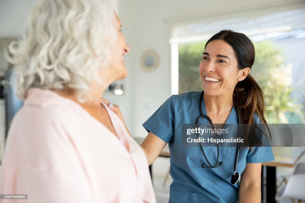 Happy doctor talking to a senior woman on a house call