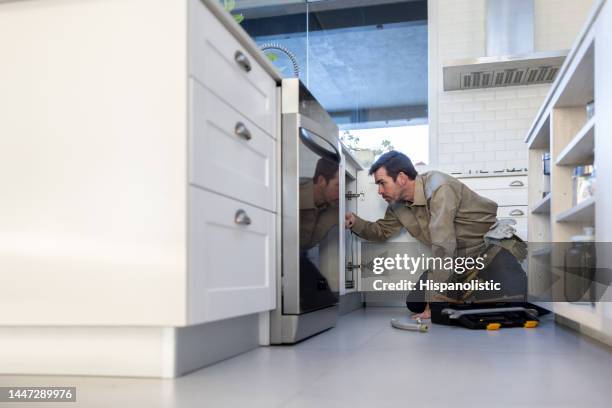 handyman fixing a cabinet door in the kitchen - handyman stockfoto's en -beelden