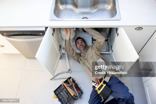 plumber fixing a leak in the sink in the kitchen - kitchen straighten stockfoto's en -beelden