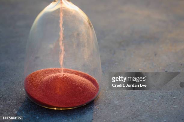 red sand hourglass on concrete floor - 砂時計　無人 ストックフォトと画像