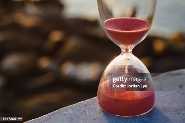 sand flowing through an hourglass - contrarreloj fotografías e imágenes de stock