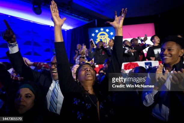 Darlene Butler Jones and other supporters react as they hear the results at an election night watch party for Sen. Raphael Warnock at the Marriott...
