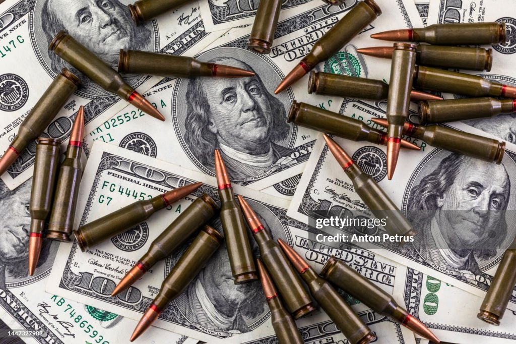 100 dollar bills and machine gun cartridges. Concept of economic crisis due to war
