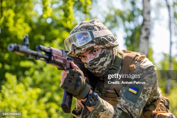 ukrainian soldier with kalashnikov assault rifle in the forest - ammunition stock-fotos und bilder