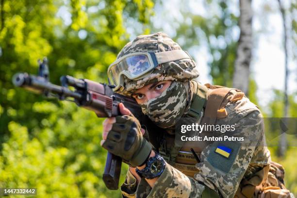 ukrainian soldier with kalashnikov assault rifle in the forest - oorlog stockfoto's en -beelden
