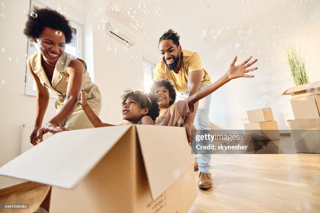 Familia negra despreocupada divirtiéndose después de mudarse a un nuevo hogar.