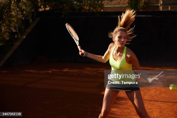 young adult woman tennis player hitting forehand shot with ponytail in the air - making rounds stock pictures, royalty-free photos & images