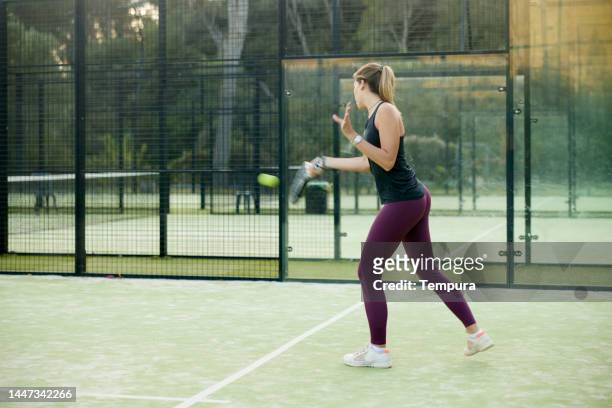 jeune femme adulte prenant un coup de feu en jouant au padel sur un terrain de sport - paddle tennis photos et images de collection