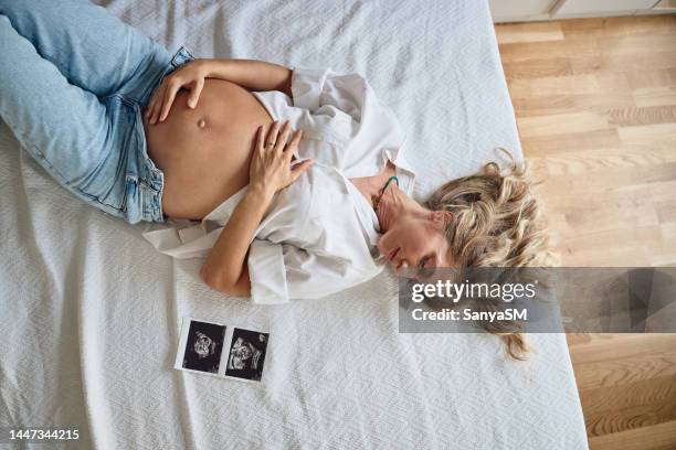 pregnant woman embracing her belly - twin ultrasound stock pictures, royalty-free photos & images