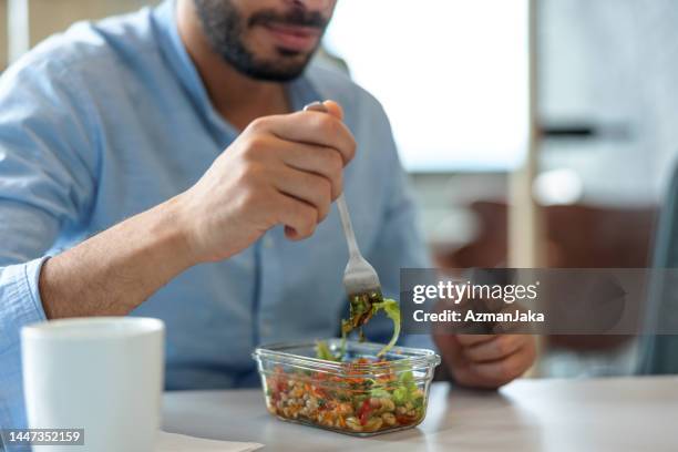 closeup of the hands of a middle-eastern man eating a healthy salad at the office - middle eastern food stockfoto's en -beelden