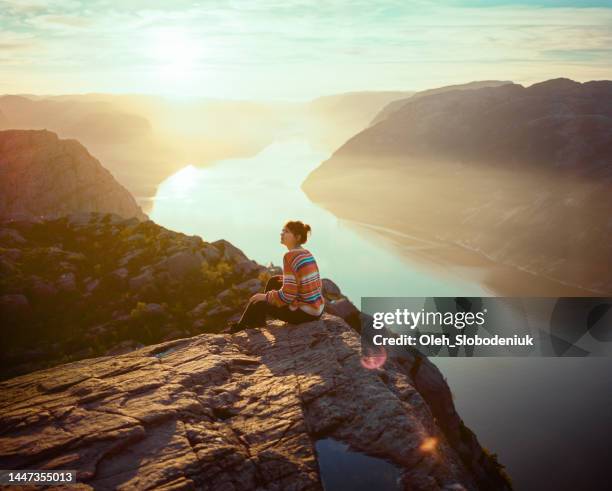 woman sitting in mountains on the background of lysefjorden - solo travel stock pictures, royalty-free photos & images