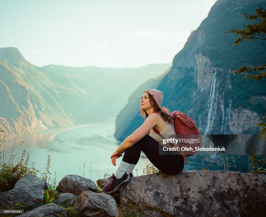 Woman sitting near Seven sisters waterfall in mountains in Norway