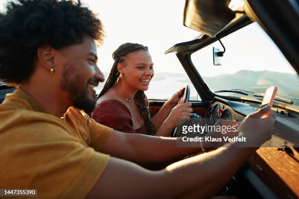 man sharing mobile phone with girlfriend in car - gedeelde mobiliteit stockfoto's en -beelden