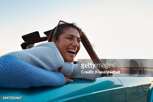 Happy woman in car on road trip