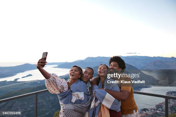 woman taking selfie with friends on smart phone - holiday fun stock pictures, royalty-free photos & images