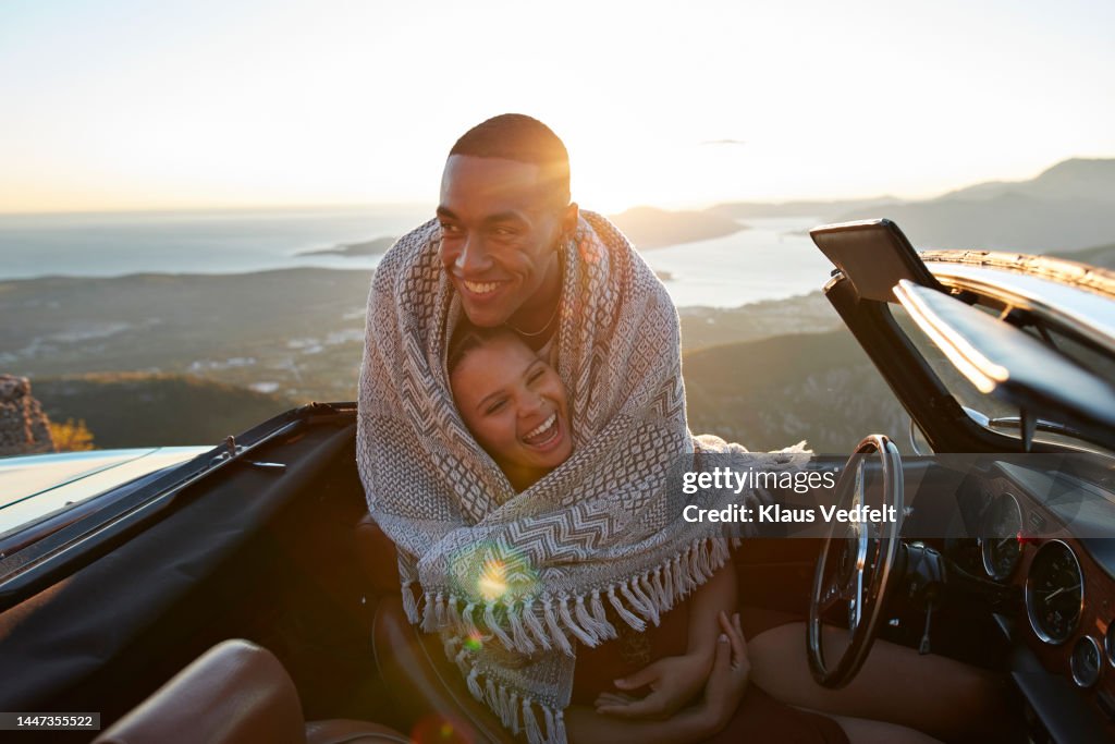 Man embracing girlfriend in convertible car