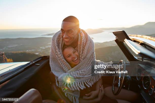 man embracing girlfriend in convertible car - couple short hair stock pictures, royalty-free photos & images